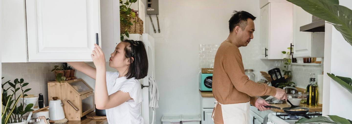 Father and daughter making breakfast together in white kitchen