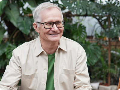 Older man smiling with plants in background