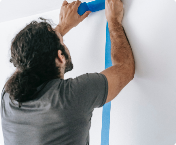 Man applying painters tape on wall