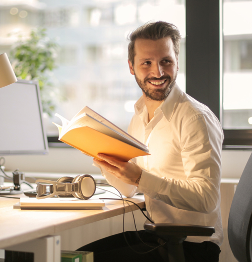 Man sitting at desk and holding book smiling