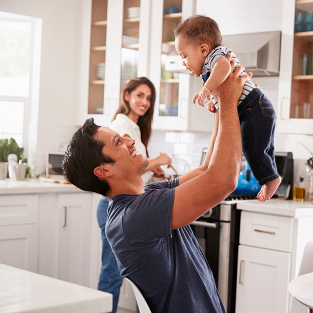 Young dad holding baby in air in the kitchen