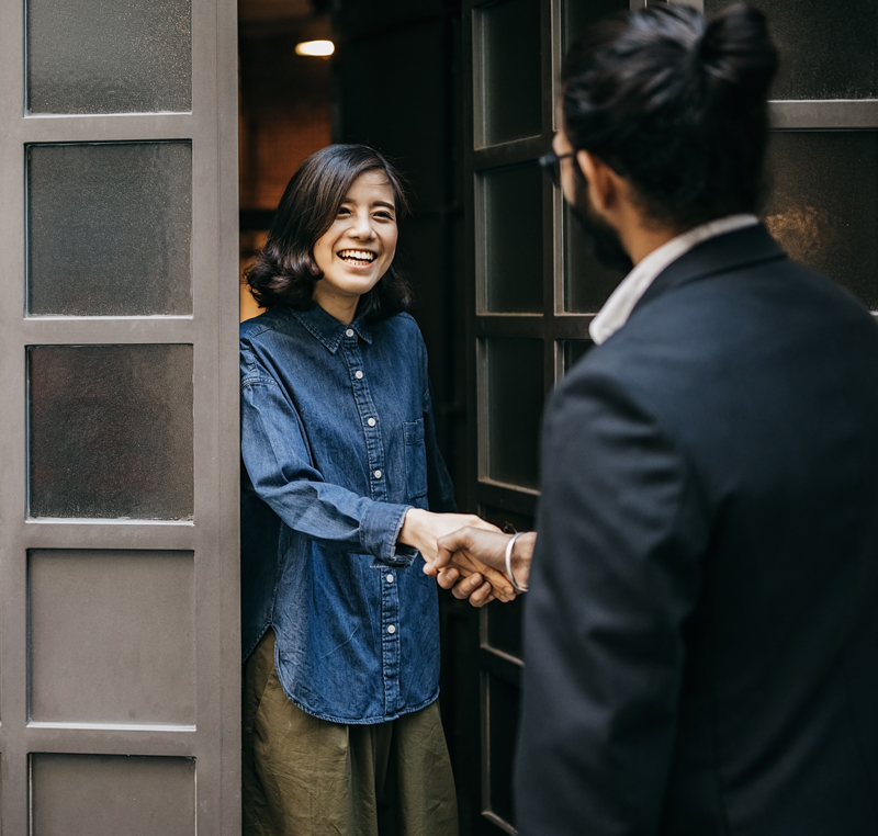 Woman greeting a man at her door and shaking hands